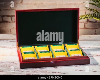 Tee in Holzkiste auf wunderschönem Hintergrund. Sammlung von Teebeuteln in Holzbox. Fruchtteebeutel in Beuteln, bunte Teebeutel in einer Box Stockfoto