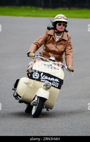 Frauen in Vintage-Kleidung auf einem klassischen Vespa-Motorroller bei der Goodwood Revival Vintage Nostalgie-Veranstaltung in Großbritannien. Vespa Club Milano Stockfoto