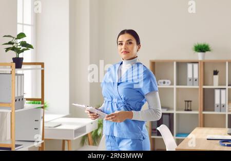 Porträt einer jungen Ärztin in blauer medizinischer Uniform, die in die Kamera schaut. Stockfoto