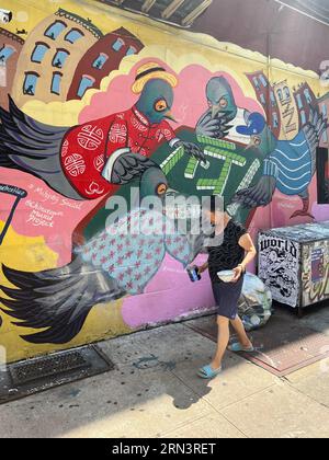 Mahjong Social September 2020 4 Orchard St, New York, New York Was schreit mehr New York als eine Gruppe von Tauben, die Brettspiele auf den Straßen spielen? Mahjong Social, der zweite Teil des Chinatown Mural Project, erkennt die Geschichte der chinesischen und jüdischen Einwanderergruppen, die sich in der Gegend niederließen. Mahjong – das beliebte und klassische chinesische Fliesenspiel war auch bei jüdischen Gemeinden sehr beliebt. Neben Partygästen auf den Dächern und den Fahnen in den Fenstern, können Sie den versteckten Pfirsich finden? Stockfoto