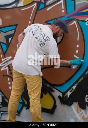 Ein Graffiti-Künstler, der irgendwo in Brüssel, Belgien, an einer Betonwand arbeitet. Bunte Straßenkunst Stockfoto