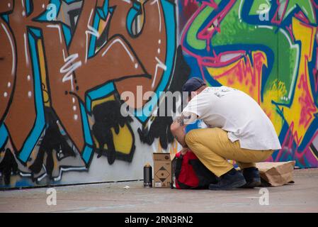 Ein Graffiti-Künstler, der irgendwo in Brüssel, Belgien, an einer Betonwand arbeitet. Bunte Straßenkunst Stockfoto