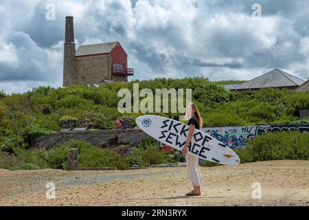 Surfer Tabitha McCormick Surf Board mit dem SLOGAN „SICK OF SEWAGE“ und Surfer Against Sewage HQ in St Agnes, Cornwall, UK Stockfoto