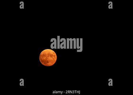 Fesselnder roter Mond über Südfrankreich am 30. März 2023, mit viel Kopierraum im dunklen Himmel. Stockfoto