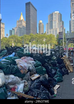 Es ist ein ziemlicher Kontrast, wenn man den wöchentlichen Müll an der Bordsteinkante sieht, die zur Abholung auf der 24th Street bereit ist, und die hohen Gebäude der Stadt, die im Hintergrund aufragen. Manhattan, New York City. Stockfoto