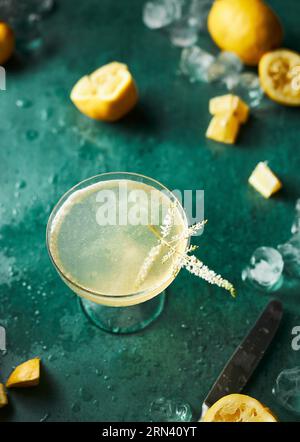 Erfrischender Cocktail auf blauem Hintergrund. Viele Zitronen und Eis. Sommergetränk. Unordentliche natürliche Atmosphäre, als ob ein Cocktail zubereitet würde. Stockfoto