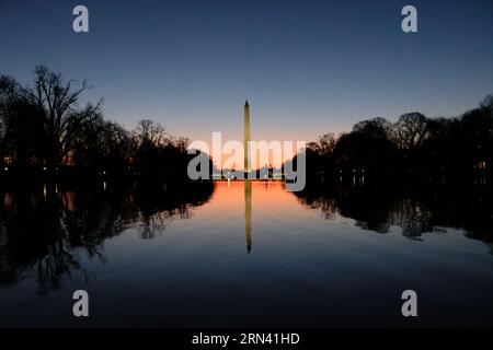 Washington Monument Reflecting Pool Washington DC // WASHINGTON DC – das Washington Monument spiegelt sich bei Sonnenaufgang im ruhigen Wasser des Reflecting Pools wider. Das Licht am frühen Morgen taucht die National Mall in ein warmes Licht, das den berühmten Obelisken hervorhebt und eine ruhige und malerische Szene schafft. Das Washington Monument, eines der bekanntesten Wahrzeichen der Vereinigten Staaten, ist eine Hommage an den ersten Präsidenten der USA, George Washington. Stockfoto