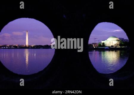 Washington Monument Jefferson Memorial Tidal Basin Washington DC // WASHINGTON, D.C., Vereinigte Staaten – Ein einzigartiger Blick auf das Washington Monument und das Jefferson Memorial, eingerahmt von den runden Portalen der Ohio Drive Bridge in der Vordämmerung. Die berühmten Wahrzeichen spiegeln sich in den stillen Gewässern des Tidal Basin wider und schaffen eine ruhige und symmetrische Komposition. Stockfoto