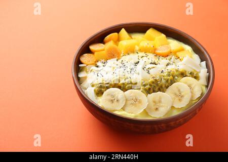 Leckere Smoothie-Schüssel mit frischem Obst auf Orangentisch. Leerzeichen für Text Stockfoto