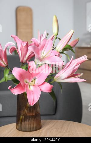 Wunderschöne rosa Lilienblüten in Vase auf Holztisch zu Hause Stockfoto