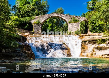 Die mittelalterliche Brücke Ponte della Brusia über den Fluss Fiume Montone und den Wasserfall in Bocconi in Emilia-Romagna, Italien Stockfoto