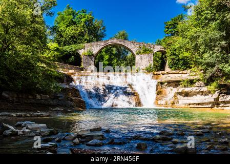 Die mittelalterliche Brücke Ponte della Brusia über den Fluss Fiume Montone und den Wasserfall in Bocconi in Emilia-Romagna, Italien Stockfoto