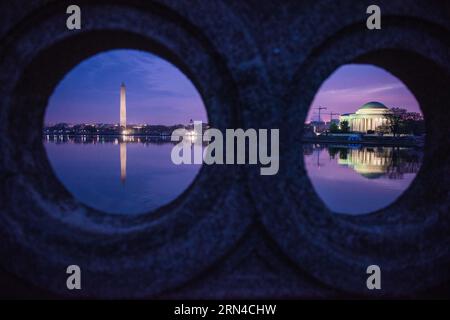 Washington Monument Jefferson Memorial Tidal Basin Washington DC // WASHINGTON, D.C., Vereinigte Staaten – Ein einzigartiger Blick auf das Washington Monument und das Jefferson Memorial, eingerahmt von den runden Portalen der Ohio Drive Bridge in der Vordämmerung. Die berühmten Wahrzeichen spiegeln sich in den stillen Gewässern des Tidal Basin wider und schaffen eine ruhige und symmetrische Komposition. Stockfoto