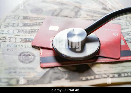 Stethoskop mit Bank- und Kreditkarte. Stethoskop auf Kreditkarte mit Dollarrechnungen, Konzept der ärztlichen Online-Bezahlung mit Kreditkarte Stockfoto