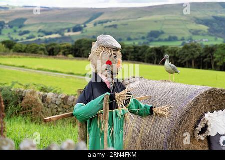 Vogelscheuche auf einem Bauernfeld fröhliches lächelndes Gesicht mit flacher Kappe und grünen Overalls Stockfoto