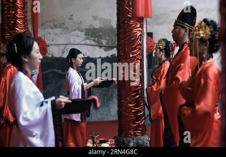 (150520) -- RUCHENG, 20. Mai 2015 -- Dienerinnen im weißen Kleid dienen den Bräuten während einer gemeinsamen traditionellen Han-Hochzeit in einer Vorfahrthalle in Rucheng, Provinz Hunan in Zentralchina, 20. Mai 2015. Der 20. Mai wird in chinesischer Sprache ähnlich wie wo ai Ni ausgesprochen, was „Ich liebe dich“ bedeutet, und am Mittwoch fand eine traditionelle Gruppenhochzeit für 10 Paare im Ahnensaal in Rucheng statt. Die Ahnensaal ist ein chinesischer Tempel, der vergöttlichten Ahnen und Vorfahren von Familiennamen oder Familien in der chinesischen Kultur gewidmet ist. Und heute ist der Stammsaal in Rucheng zum Prominenten geworden Stockfoto