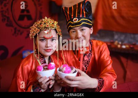 (150520) -- RUCHENG, 20. Mai 2015 -- Eine Braut und ein Bräutigam zeigen die Eier, die eine lang anhaltende Perfektion bei einer traditionellen Han-Hochzeit in einer Vorfahrthalle in Rucheng, der zentralchinesischen Provinz Hunan, am 20. Mai 2015 symbolisieren. Der 20. Mai wird in chinesischer Sprache ähnlich wie wo ai Ni ausgesprochen, was „Ich liebe dich“ bedeutet, und am Mittwoch fand eine traditionelle Gruppenhochzeit für 10 Paare im Ahnensaal in Rucheng statt. Die Ahnensaal ist ein chinesischer Tempel, der vergöttlichten Ahnen und Vorfahren von Familiennamen oder Familien in der chinesischen Kultur gewidmet ist. Und heute hat der Stammsaal in Rucheng b Stockfoto