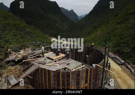 Die Menschen bauen einen 300-Kubikmeter-Wassertank, der von der lokalen Regierung im Dorf Nongyong in der Gemeinde Bansheng im Autonomen Kreis Dahua Yao, südwestchinesische autonome Region Guangxi Zhuang, am 5. Mai 2015 finanziert wird. Die Bansheng Township liegt im Zentrum der Karst-Landformen im Westen von Guangxi und leidet seit Ewigkeiten unter einem starken Wassermangel. Die Niederschläge sind daher ein Segen für die Menschen, die seit etwa 1.000 Jahren auf diesem Land leben und hauptsächlich der ethnischen Gruppe der Yao angehören. Um ihren täglichen Lebensbedürfnissen gerecht zu werden, sammeln die Einheimischen immer Regenwasser mit Eimern und Fässern jeder Größe sowie Dächern Stockfoto