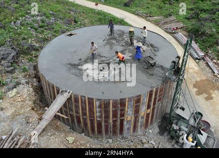 Die Menschen bauen einen 300-Kubikmeter-Wassertank, der von der lokalen Regierung im Dorf Nongyong in der Gemeinde Bansheng im Autonomen Kreis Dahua Yao, südwestchinesische autonome Region Guangxi Zhuang, am 6. Mai 2015 finanziert wird. Die Bansheng Township liegt im Zentrum der Karst-Landformen im Westen von Guangxi und leidet seit Ewigkeiten unter einem starken Wassermangel. Die Niederschläge sind daher ein Segen für die Menschen, die seit etwa 1.000 Jahren auf diesem Land leben und hauptsächlich der ethnischen Gruppe der Yao angehören. Um ihren täglichen Lebensbedürfnissen gerecht zu werden, sammeln die Einheimischen immer Regenwasser mit Eimern und Fässern jeder Größe sowie Dächern Stockfoto