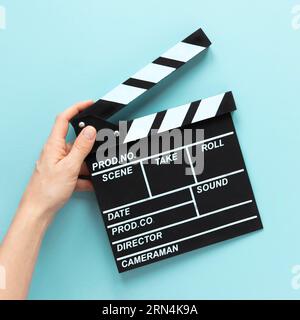 Person mit blauem Hintergrund und Filmklapper Stockfoto