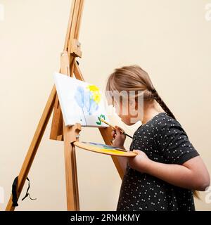Side View Girl mit Down-Syndrom Malerei mit Pinsel Stockfoto