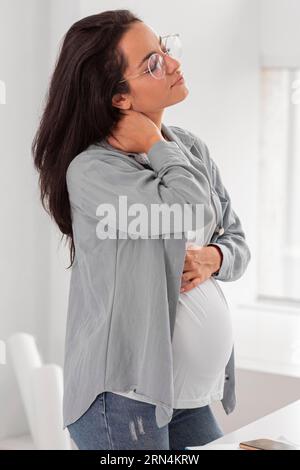 Eine schwangere Frau, die ihren Hals hält Stockfoto