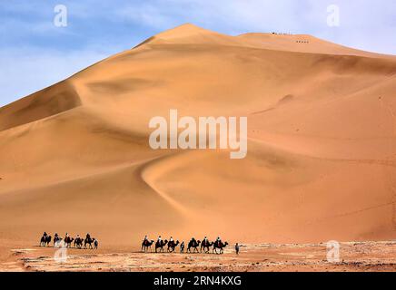 (150524) -- DUNHUANG, -- Touristen reiten auf Kamelen am malerischen Ort Mingsha Hill in der Wüste Gobi in Dunhuang, nordwestchinesische Provinz Gansu, 23. Mai 2015. Der Mingsha Hill besteht aus einer Gruppe von Sanddünen und ist berühmt für seine Wüstenlandschaft und das geheimnisvolle Geräusch, das vom Wind erzeugt wird, wenn er über seine Oberfläche bläst. ) (wf) CHINA-GANSU-DUNHUANG-TOURISM (CN) WangxSong PUBLICATIONxNOTxINxCHN Stockfoto