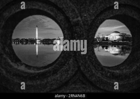 Washington Monument und Jefferson Memorial at Night, Washington, D.C. Schwarzweißfoto zeigt die Denkmäler, die sich im Wasser spiegeln, eingerahmt von einer Steinstruktur. Stockfoto