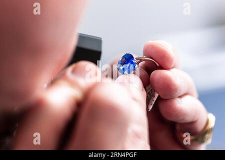 Überprüfen eines Rings mit einem Edelstein auf Authentizität Stockfoto