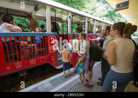 (150613) -- BUDAPEST, 13. Juni 2015 -- Passagierwarteschlange, um in den Zug am Bahnhof Huvosvolgy der Kinderbahn in Budapest, Ungarn, 13. Juni 2015 zu steigen. Die 11,7018 km lange Schmalspurbahn verkehrt zwischen den Bahnhöfen Huvosvolgy und Szechenyihegy in Budapest. Seit der Einweihung der ersten 3,2 km Gleis am 31. Juli 1948 ist es im Dauerbetrieb. Die Motoren werden von erwachsenen Ingenieuren angetrieben, und Kinder im Alter von 10 bis 14 Jahren im Dienst werden ständig von erwachsenen Eisenbahnmitarbeitern überwacht. Abgesehen davon erledigen Kinder ihre Arbeit allein. Die Kinderbahn hat den Beamten erhalten Stockfoto