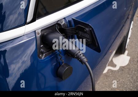 Nahaufnahmen, E-Light-Fahrzeug, Kabinenroller MICROLINO an Ladestation für Elektroautos, elektrische Ladestation, E-Tankstelle, E-Mobilität Stockfoto