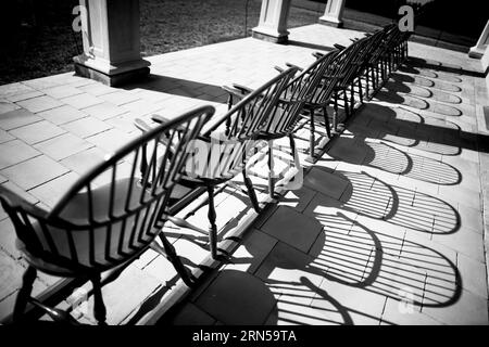 MOUNT VERNON, Virginia – traditionelle Windsor-Holzstühle säumen die ikonische piazza in George Washingtons Mount Vernon-Villa. Die Stühle, die grün gestrichen sind, passen zu den Rollläden, zeigen nach außen zum weitläufigen Rasen und dem Potomac River dahinter. Diese historische Veranda spiegelt den Lebensstil des ersten amerikanischen Präsidenten aus dem 18. Jahrhundert wider. Stockfoto