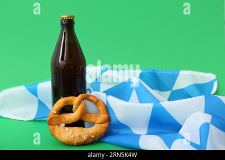 Flasche mit kaltem Bier, Flagge von Bayern und leckerer Brezel auf grünem Hintergrund. Oktoberfest Stockfoto