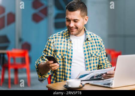 Mann mit Laptop und Smartphone-Café Stockfoto