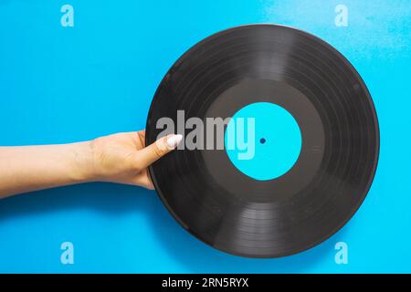 Overhead-Ansicht weibliche Hände halten Vinyl Schallplatte blauen Hintergrund Stockfoto