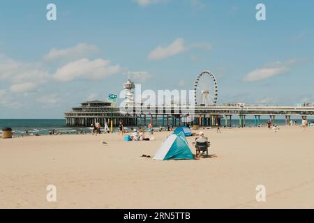 Panoramaaussicht auf den Scheveningen Strand mit Liegeplätzen, de Pier und Riesenrad im Hintergrund Stockfoto