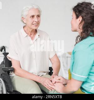 Glückliche behinderte Krankenschwester sitzen Rollstuhl suchen Hausmeister Stockfoto