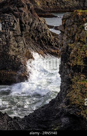 Wellen stürzen auf vulkanische Basalt-Felsformationen am Ufer in der Nähe von Arnarstapi, Snaefellsness Halbinsel, Island. Stockfoto
