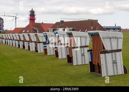 Weiße Liegen am Deich und im Hintergrund der rot-weiße Leuchtturm Buesum, Buesum, Nordfriesland, Schleswig-Holstein, Deutschland Stockfoto