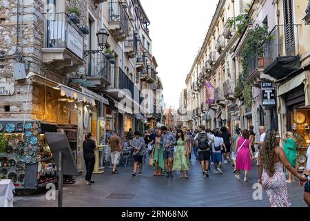 Giardini Naxos Sizilien Italien 08.07.2022 - Touristen, die am Nachmittag auf einer Gasse voller Menschen und Geschäfte spazieren gehen Stockfoto