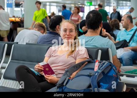 Warthalle, junge Frau wartet mit Pass und Bordkarte auf ihre Abreise, Check-in, Flughafen München, Bayern, Deutschland Stockfoto