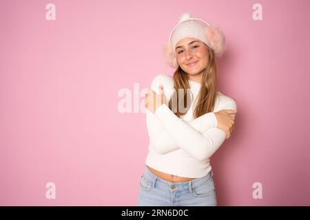 Junge schöne blonde Frau trägt lässige Winterkleidung auf rosa Hintergrund und umarmt sich glücklich und positiv, selbstbewusst lächelnd. Selbstliebe und Stockfoto