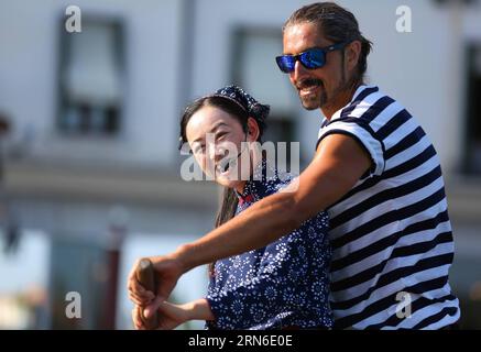 (150722) -- VENEDIG, 21. Juli 2015 -- Ein Gondolier lehrt Wu Juan (L), eine Binnenschifffrau aus Zhouzhuang, eine Gondel (ein traditionelles venezianisches Ruderboot mit flachem Boden) in Venedig, Italien, am 21. Juli 2015 zu handhaben. Während der Expo Mailand 2015 hält China s Zhouzhuang ein Seminar in Mailand und eine Veranstaltung mit dem Titel Eine Geschichte zweier Städte in Venedig ab, um die chinesische Kultur der Wasserstadt vorzustellen. )(bxq) ITALIEN-VENEDIG-ZHOU ZHUANG-BARGE FRAU JinxYu PUBLICATIONxNOTxINxCHN 150722 Venedig 21. Juli 2015 ein Gondolier lehrt Wu Juan l eine Barge Frau aus Zhou Zhuang, eine Gondel zu handhaben, eine traditionelle venezianische Reihe mit flachem Boden Stockfoto