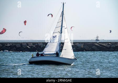 Segelboot verlässt den Hafen von Scheveningen, Kitesurfer, Niederlande Stockfoto