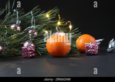 Silvester Stillleben Zweig der Kiefer neben den Mandarinenkonen Silber brennt Kranz auf schwarzem Hintergrund mit einem Platz für Text mit Stockfoto