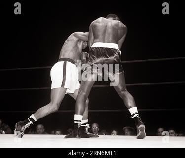 1950ER JAHRE RÜCKANSICHT ZWEI AFROAMERIKANISCHE BOXER SCHWERER BOUT ARCH RIVALEN JERSEY JOE WALCOTT LEICHTE TRUNKS VS EZZARD CHARLES DARK - P1397 HAR001 HARS BERUFE VON HINTEN PUGILIST RIVALEN JOE PUGILISM RÜCKANSICHT BOUT CHARLES MITTELERWACHSENE MÄNNER TRUNKS SCHWARZ-WEISS HAR001 ALTMODISCHE AFROAMERIKANER Stockfoto