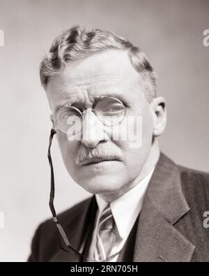 1930ER JAHRE ERNSTHAFTES PORTRÄT EINES MANNES MITTLEREN ALTERS, DER PINCE-NEZ TRÄGT - S.3928 HAR001 HARS SENIOR ADULT EXPRESSIONS MIDDLE-AGED B&W MAN EYE KONTAKT SCHNURRBART MEAN ANZUG UND KRAWATTE OLDTIMER KOPF UND SCHULTERN OLDSTER SCHNURRBART STOLZ PINCE-NEZ GESICHTSBEHAARUNG GEHOBENE ÄLTERE STILVOLLE, AUFRICHTIGE, FEIERLICHE, FOKUSSIERTE INTENSIVE SCHWARZ-WEISS-TECHNOLOGIE, SORGFÄLTIGE KAUKASISCHE ETHNIZITÄT, ERNSTHAFTE HAR001-INTENTION, ALTMODISCHES, UNLÄCHELNDES DESIGN Stockfoto