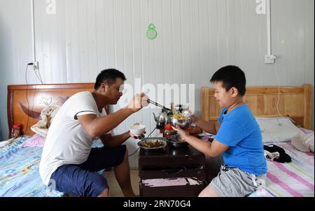 (150812) -- NANNING, 12. August 2015 -- der 8-jährige Xiao Nan, der aus der ostchinesischen Provinz Jiangxi kommt, isst mit seinem Vater auf einer Baustelle in Nanning, der Hauptstadt der südchinesischen autonomen Region Guangxi Zhuang, 12. August 2015. Fast eintausend Bauarbeiter aus dem ganzen Land arbeiten auf der Baustelle der Lianqing Bridge in Nanning City, weit weg von ihren Kindern und ihrem Zuhause. Einige Kinder können nicht bis zum Frühlingsfest warten, das einzige Mal, dass ihre Eltern nach Hause zurückkehren, kamen aber während ihres Sommerurlaubs nach Nanning, um sich wiederzusehen.) (MT) CHINA-NANNING-CONSTRUCTION SITE-FAM Stockfoto