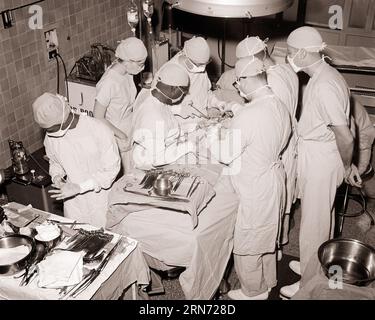 1960ER JAHRE 1970ER JAHRE ÄRZTE CHIRURGEN KRANKENSCHWESTERN STERILE KITTEL KAPPEN MASKEN DURCHFÜHRUNG VON OPERATIONEN IM OPERATIONSSAAL DES KRANKENHAUSES - M8451 HAR001 HARS RISIKOSICHERHEIT B&W HEALTHCARE OPERATIONSCHIRURGIE WEITWINKEL OPERATIONSPRÄVENTION KOPF UND SCHULTERN HOHER WINKEL STERILE KRAFT HEILUNG AFROAMERIKANER AFROAMERIKANER DIAGNOSE CHIRURGISCHES WISSEN CHIRURGEN SCHWARZE ETHNISCHE KITTEL OP-RAUM GESUNDHEITSWESEN BEHÖRDE BEHINDERUNG BERUFE CHIRURG BEHANDLUNG KONZEPTIONELLE CAPS KRANKENHÄUSER OPERATION STILVOLLE EINRICHTUNGEN ODER ZUSAMMENARBEIT SCHWARZ-WEISS KAUKASISCHE ETHNISCHE KRANKHEIT HAR001 ALTMODISCH Stockfoto