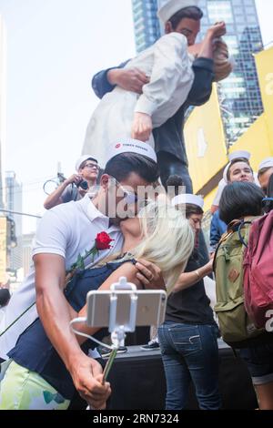 Ein Paar nimmt Selfie, während sie sich küssen, um den V-J Day Kiss am Times Square in New York, USA, am 14. August 2015 nachzustellen. Hunderte von Paaren nahmen am Freitag an den Feierlichkeiten Teil, die den Kuss zwischen einem amerikanischen Seemann und einer Krankenschwester nachahmen, den der Fotograf des Life Magazine Alfred Eisenstaedt vor 70 Jahren aufgenommen hatte, als die Amerikaner den V-J-Tag am Times Square feierten, der den Sieg über Japan markierte, der den Krieg 1945 beendete. US-NEW YORK-TIMES-SIEG IM Zweiten Weltkrieg LixMuzi PUBLICATIONxNOTxINxCHN ein PAAR nimmt Selfie mit, als sie sich küssen, um den V J Day Kiss auf dem Times Square in New York nachzustellen Stockfoto